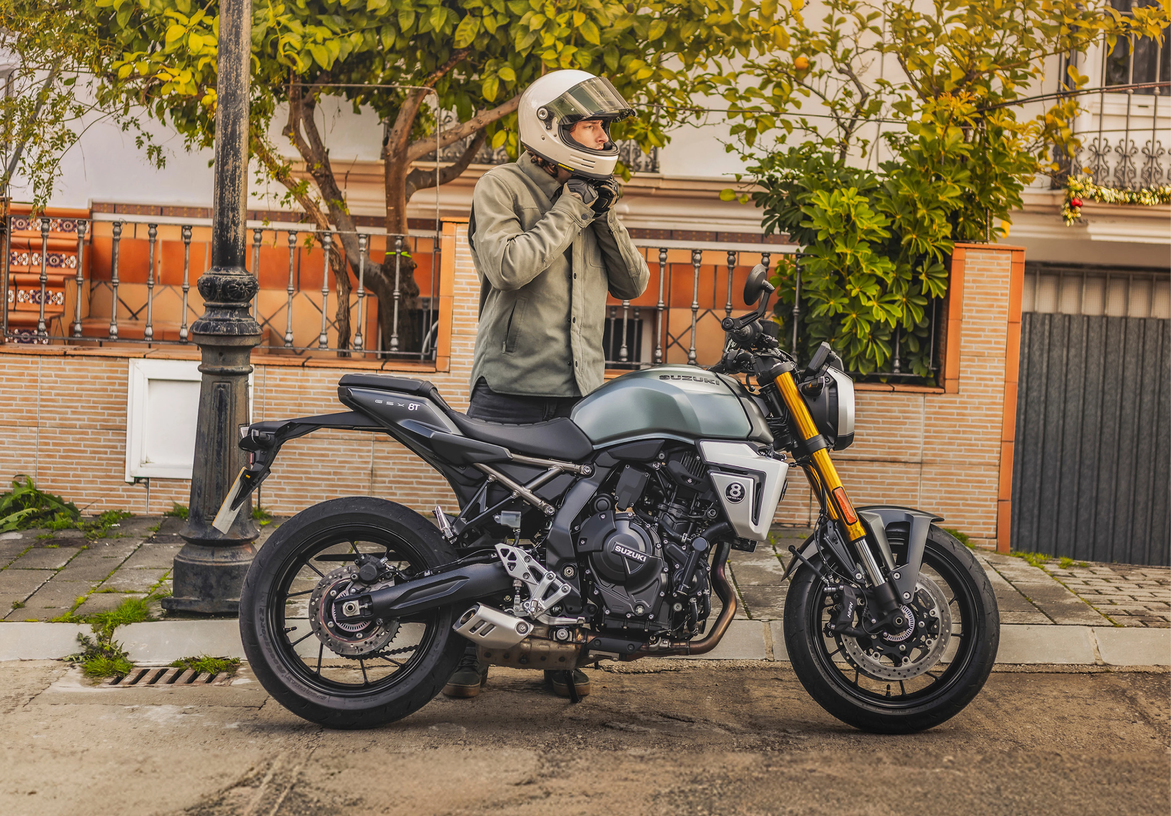 Suzuki GSX-8T right hand side static with rider taking off helmet behind. 