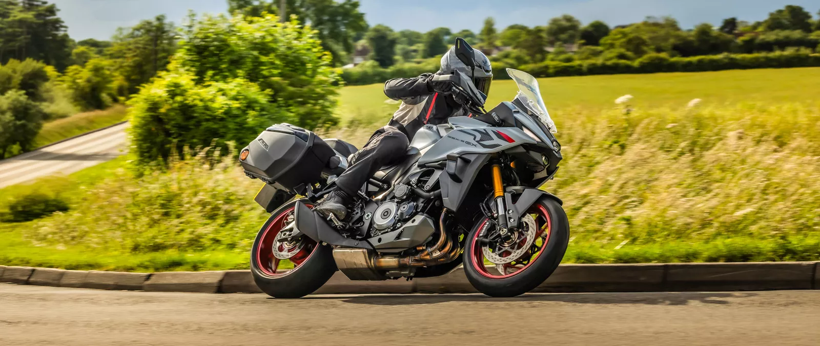 Suzuki GSX-S1000GX+ heading round a corner with country fields in the background.