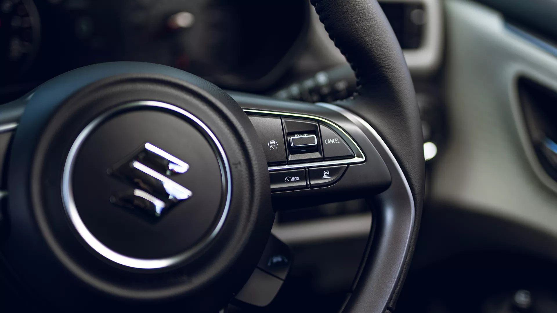 Close-up of the Suzuki Swift steering wheel controls, highlighting the cruise control and speed limiter functions