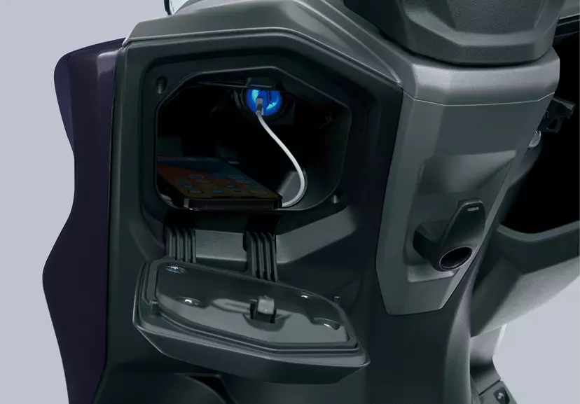Suzuki Burgman Street 125EX open storage compartment, with a USB charger, providing convenient charging options for riders.