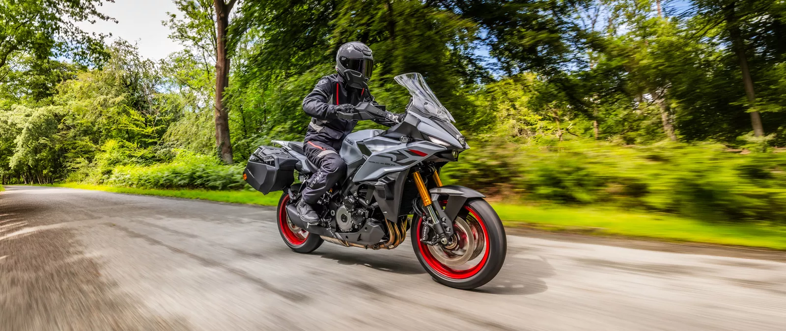 Suzuki GSX-S1000GX+ travelling along a tree lined road
