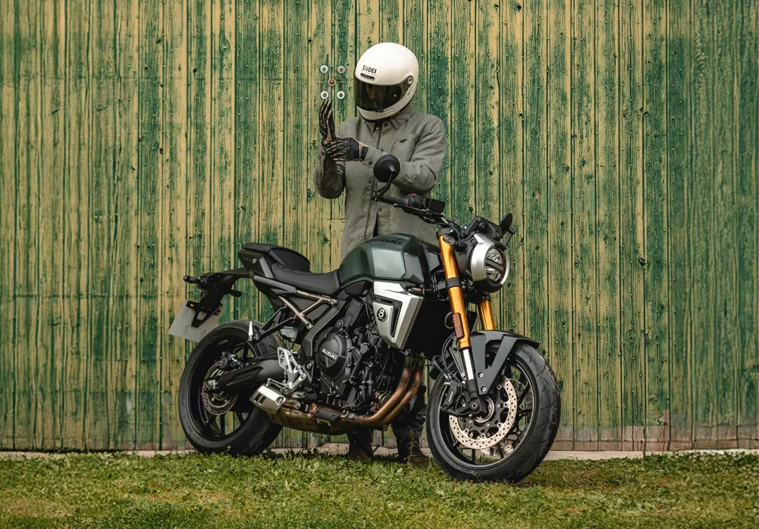 Suzuki GSX-8T static on front a green barn door with rider behind the bike