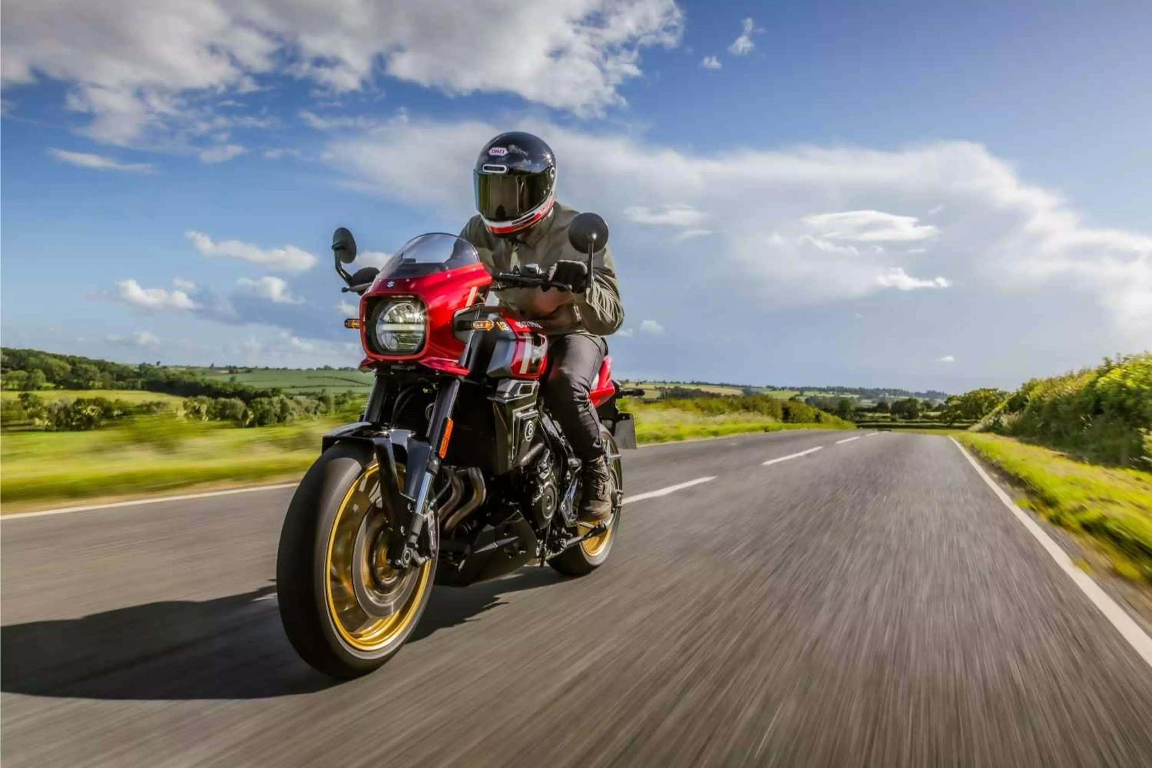 A red Suzuki 8TT riding on an A-road in the countryside