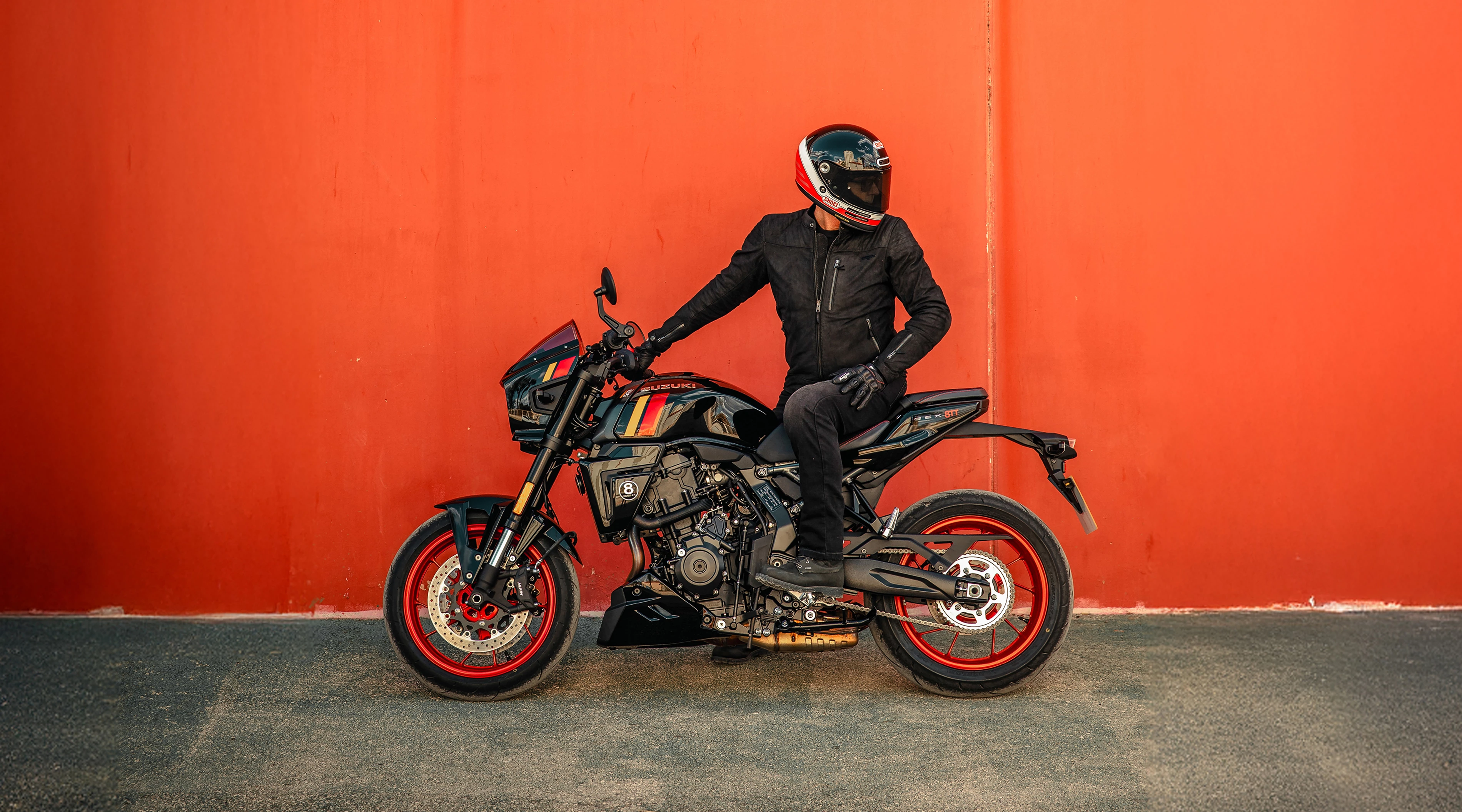 Suzuki GSX-8TT static left hand side with a red wall behind