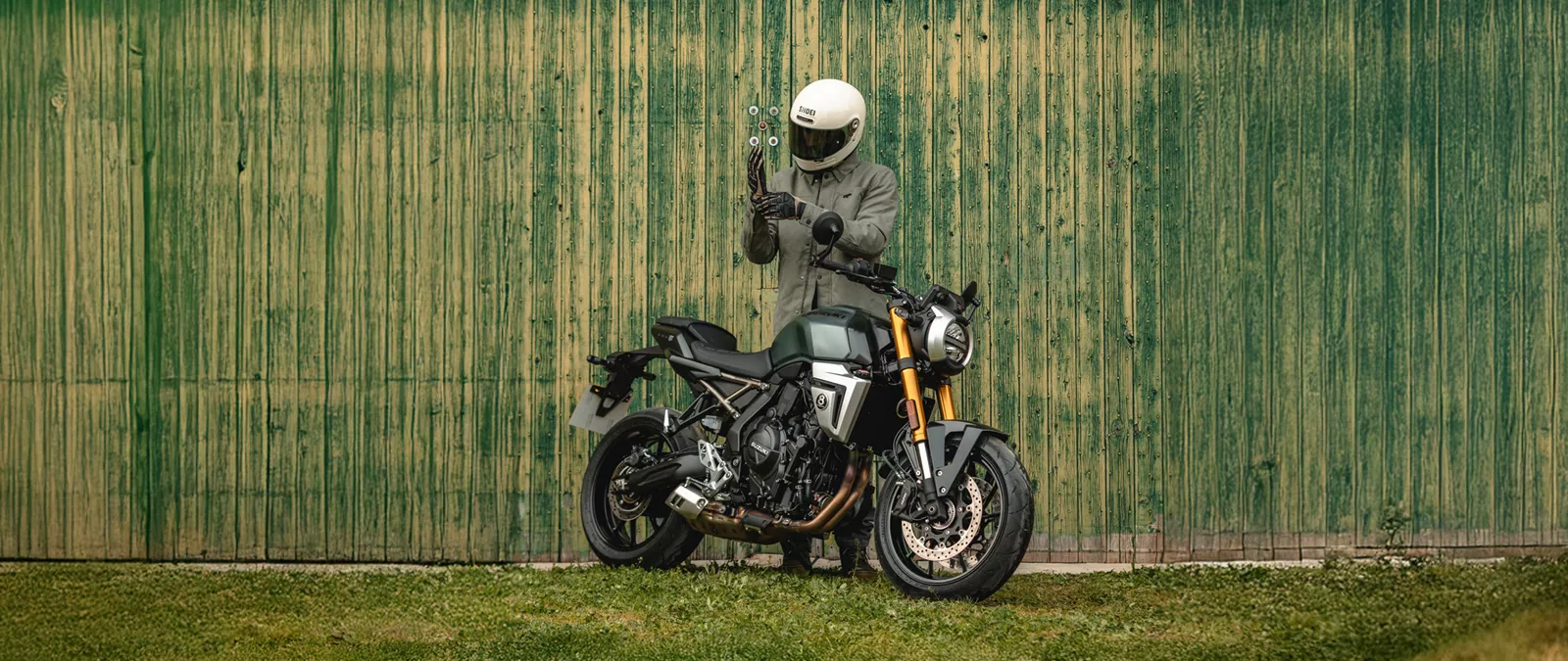 Suzuki GSX-8T green, static on front a green barn door with rider behind the bike