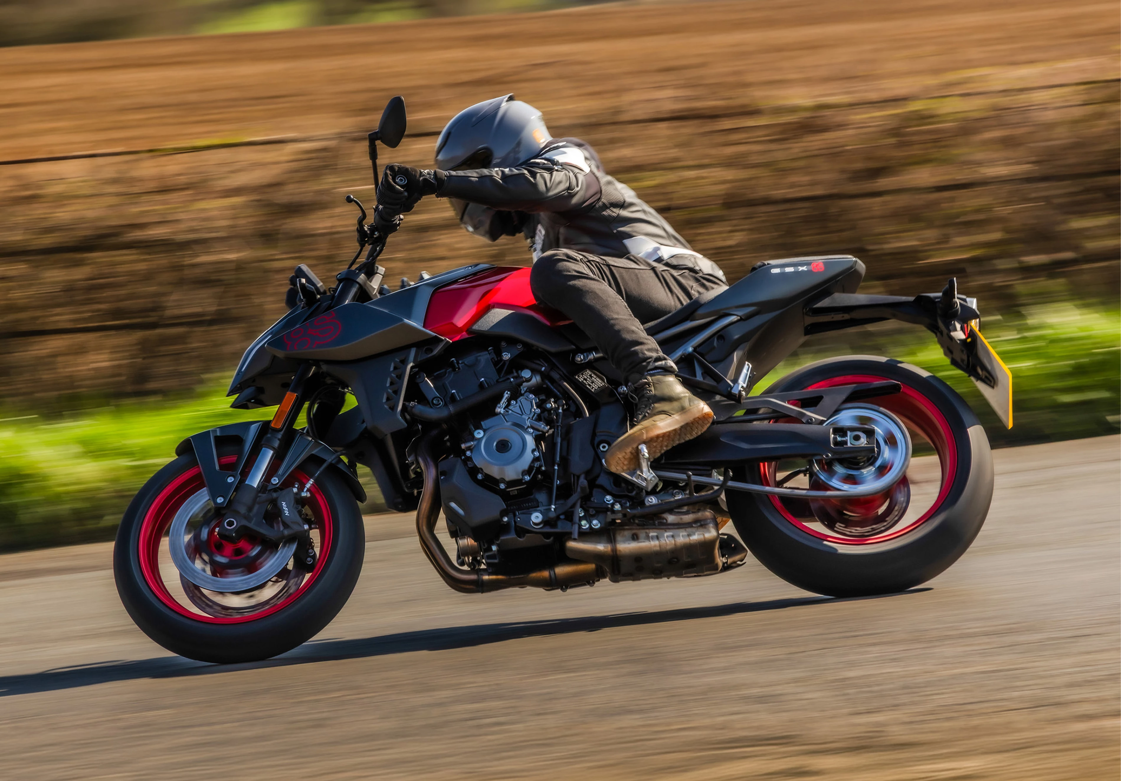 Suzuki GSX-8S red and black, leaning into a corner on a country road