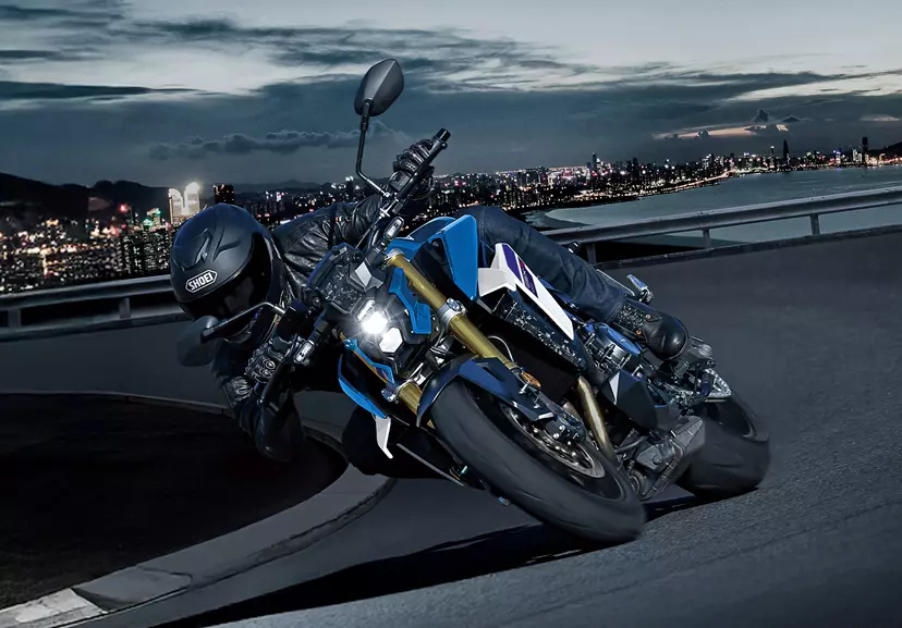 Suzuki GSX-S1000 slightly leaning into a corner at night on the outskirts of a city