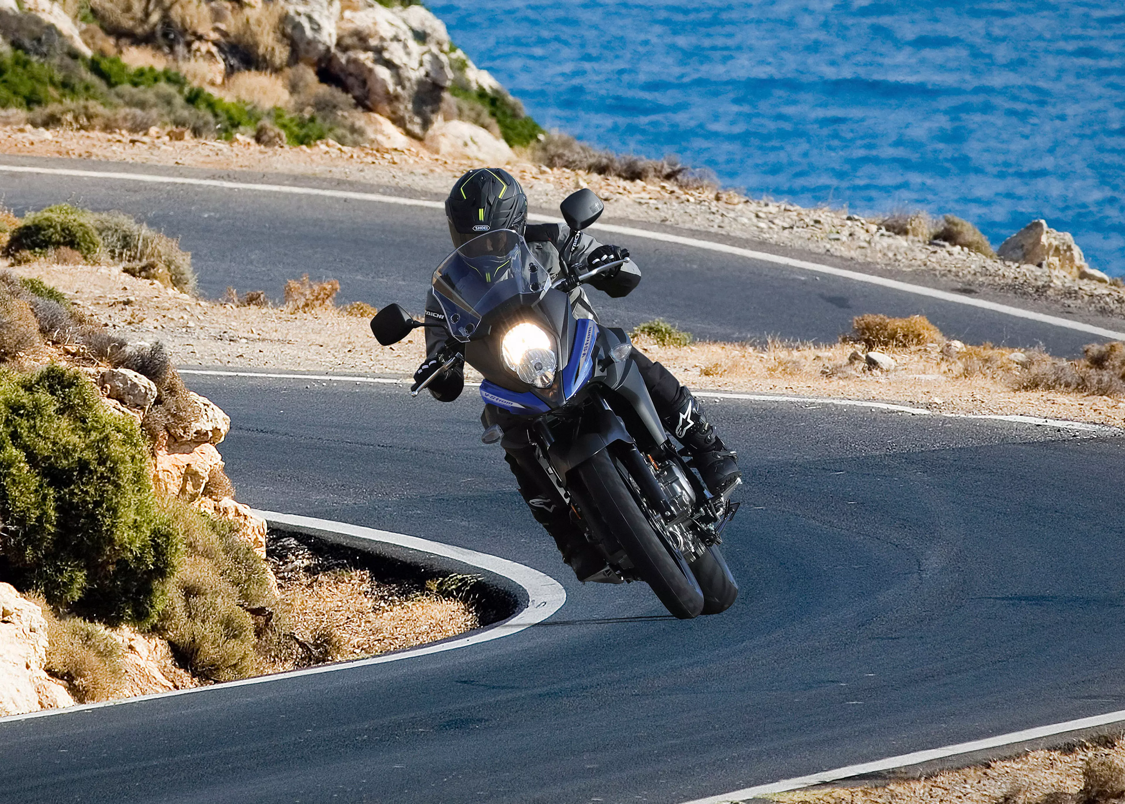 Suzuki V-Strom 650 on a twisty mountain road with the sea in the background