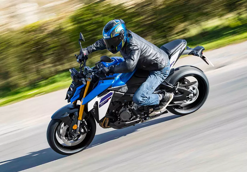 Suzuki GSX-S1000 leaning into a corner with a countryside background.