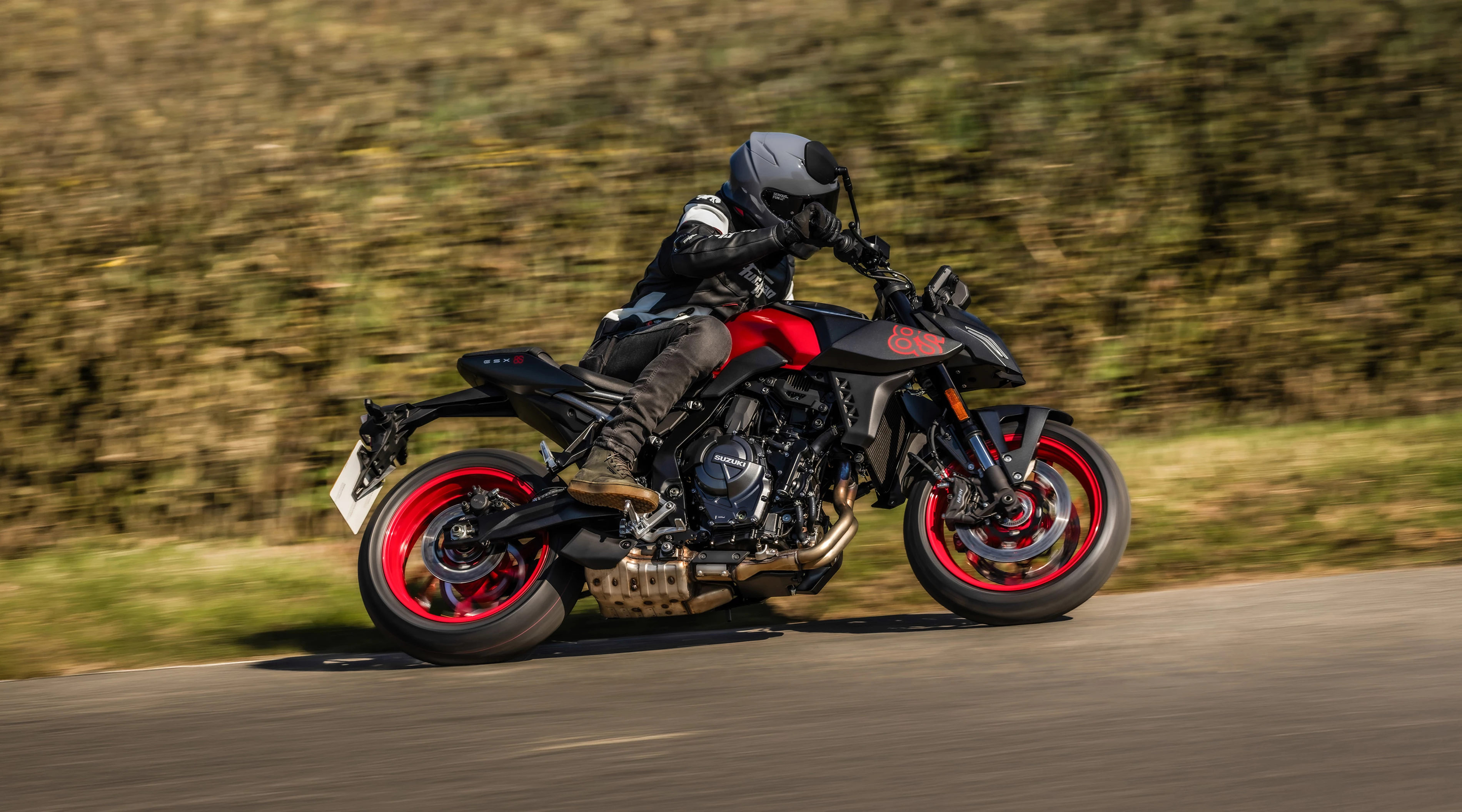 Suzuki GSX-8S red and black, leaning into a corner on a country road
