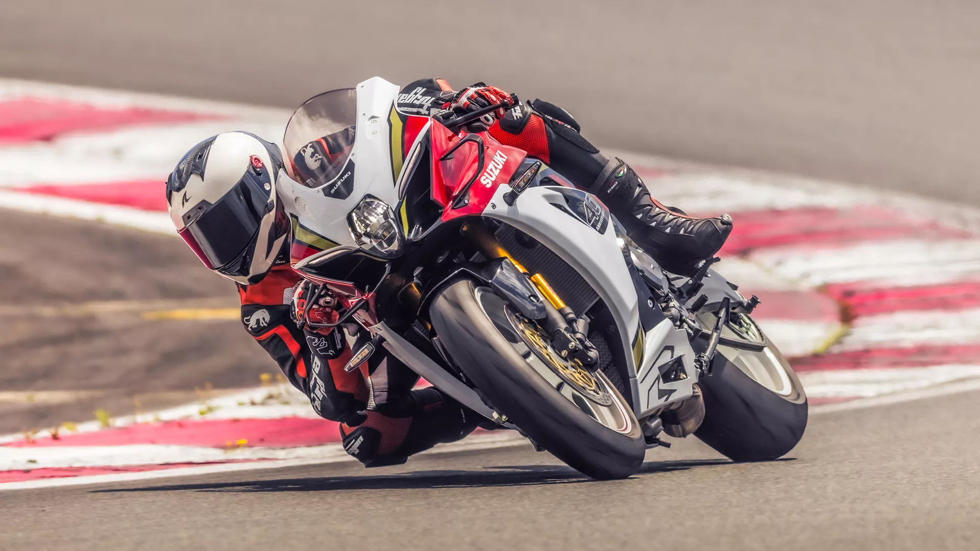 Suzuki GSX-R1000R red, leant over pushing hard coming out of a corner on track