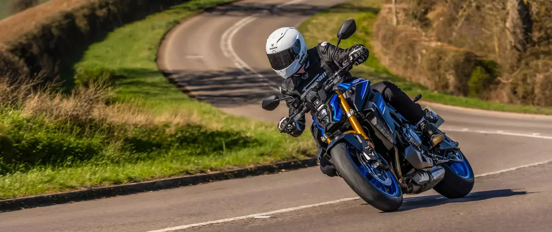 Suzuki GSX-S1000 leaning hard into a corner on a country road.