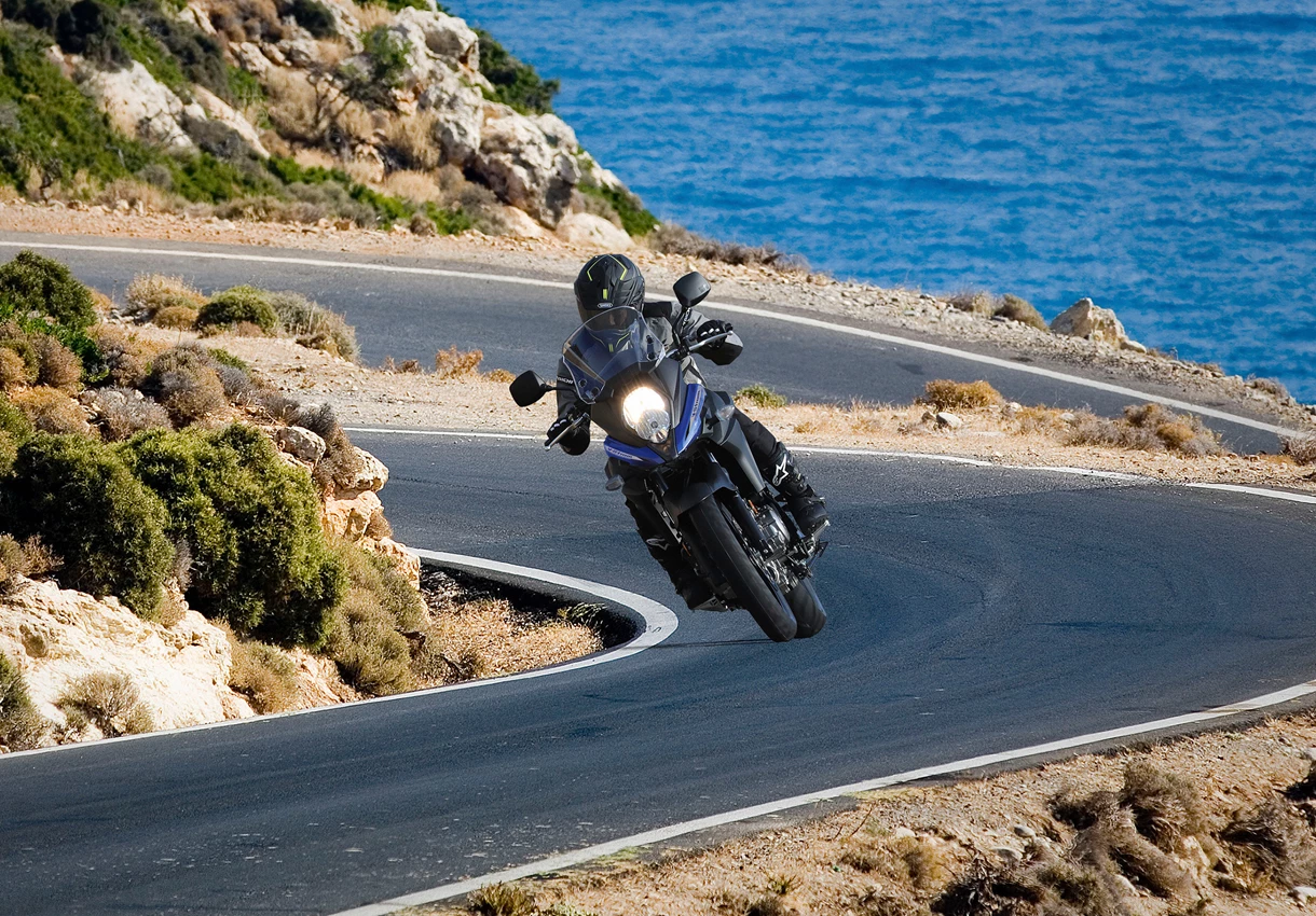 Suzuki V-Strom 650 on a twisty mountain road with the sea in the background