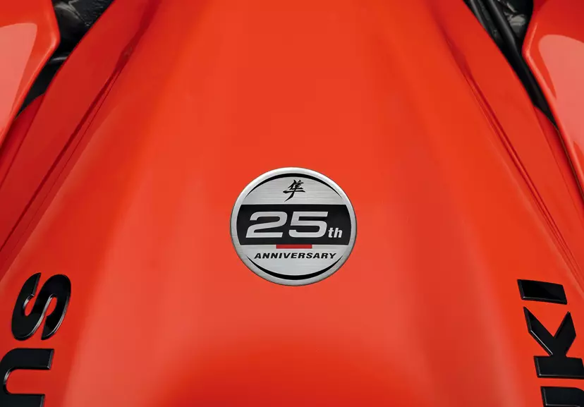 Close-up of the Suzuki 25th anniversary badge on an orange Hayabusa motorcycle tank.