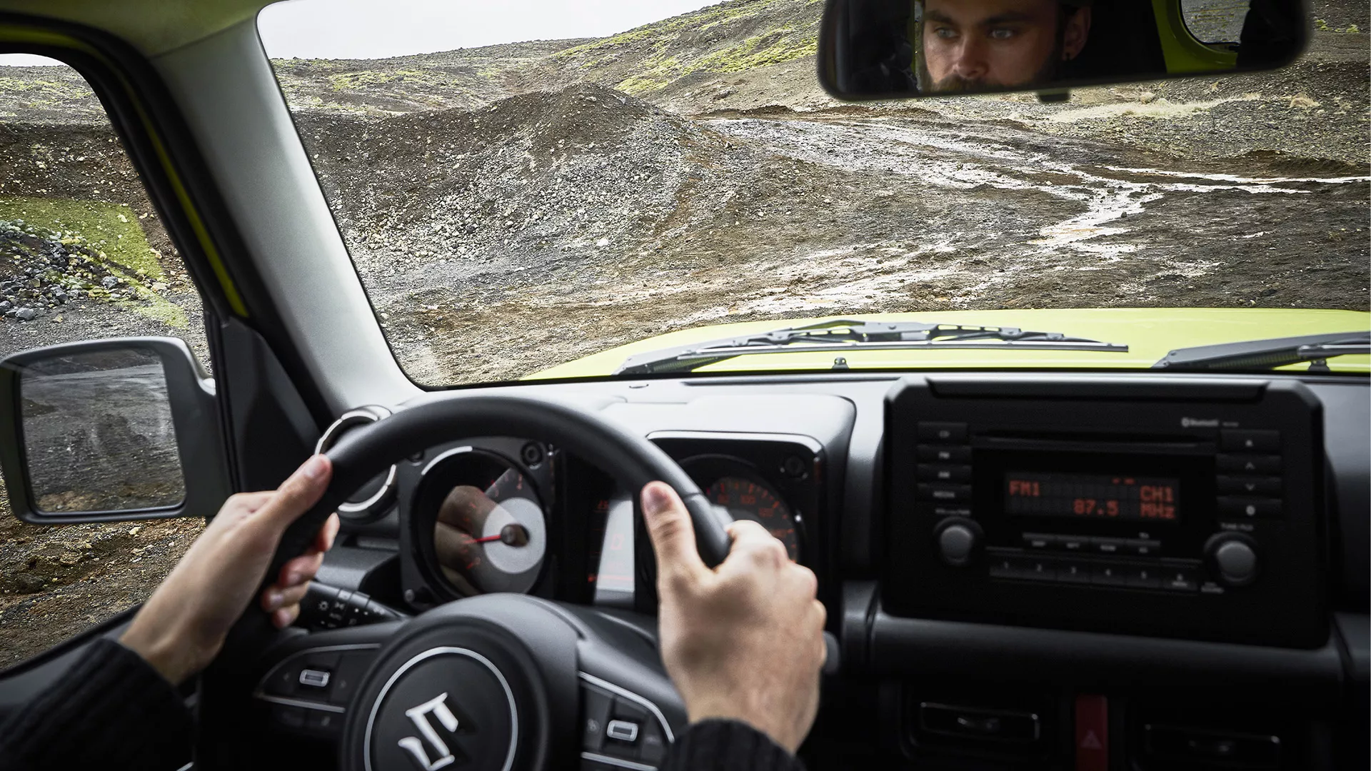 Interior view of Suzuki Jimny being driven off-road, highlighting ALLGRIP Pro 4WD and rugged terrain capability.