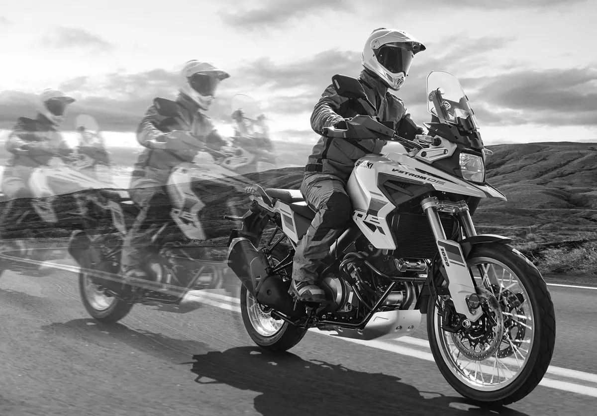 Suzuki V-Strom 1050DE riding along a mountain road with transparent bikes behind demonstrating motion