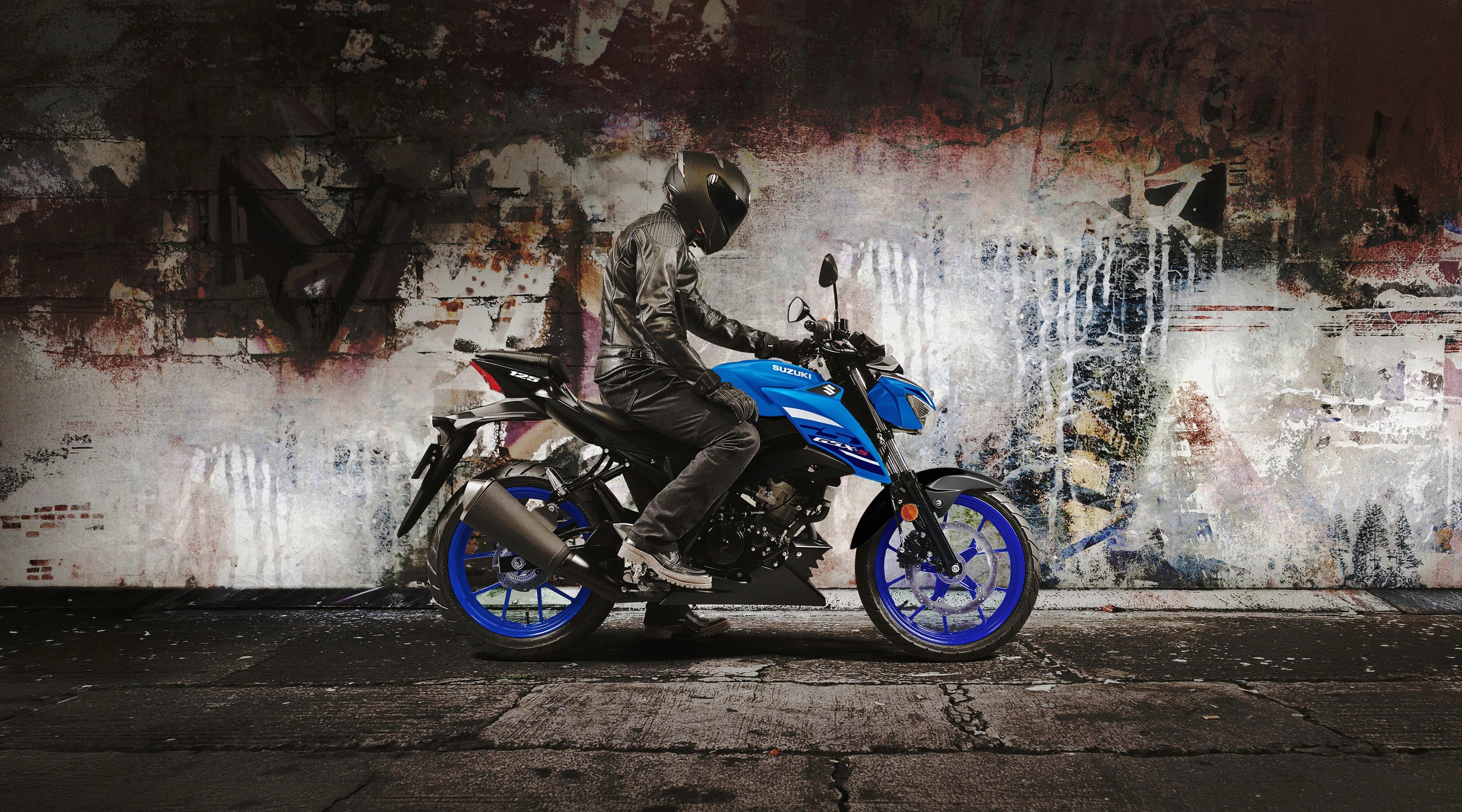 Suzuki GSX-S125 right hand side with a rider about to set off and a graffiti wall behind