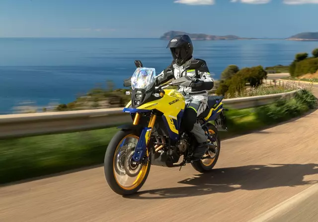 Suzuki V-Strom 800DE Tour riding along a coastal road with the sea in the background.