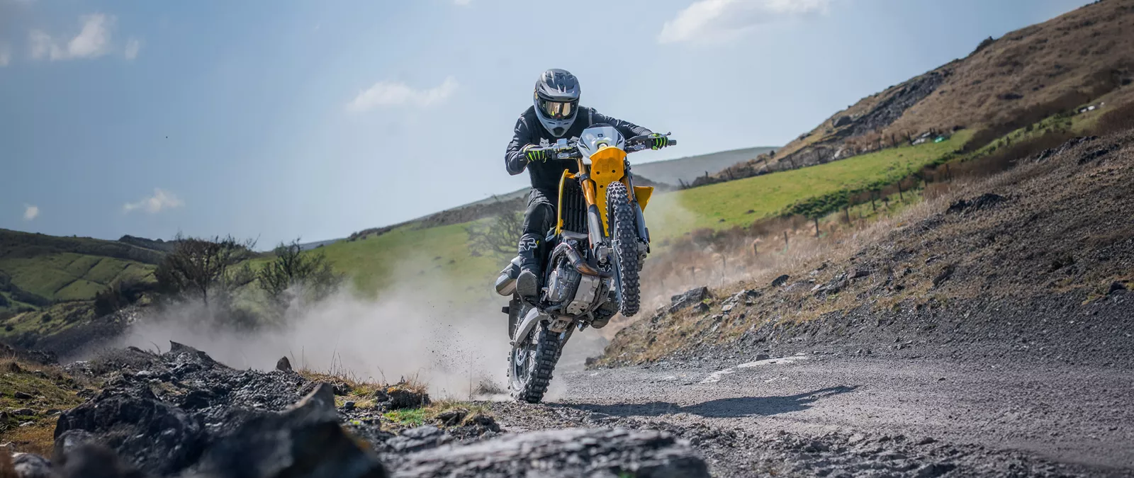 Suzuki DR-Z4S yellow, pulling a wheelie on a dirt track