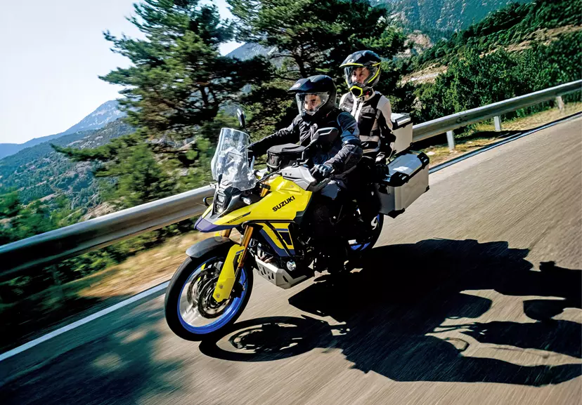 A front three-quarter view of the Suzuki V-Strom 800DE in motion on an urban country road