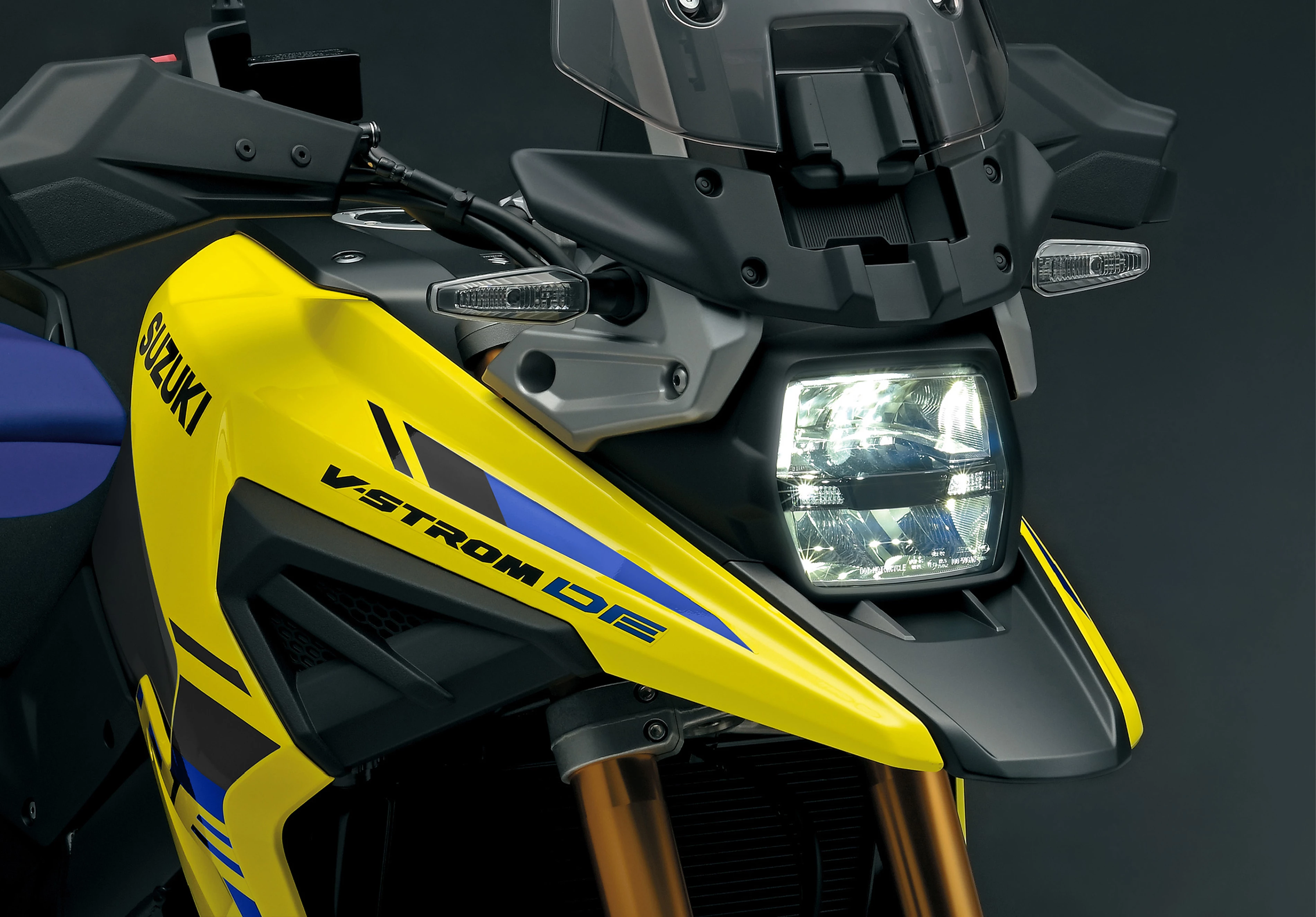 Suzuki V-Strom 1050DE Tour front end close up of LED headlight, illuminated. 