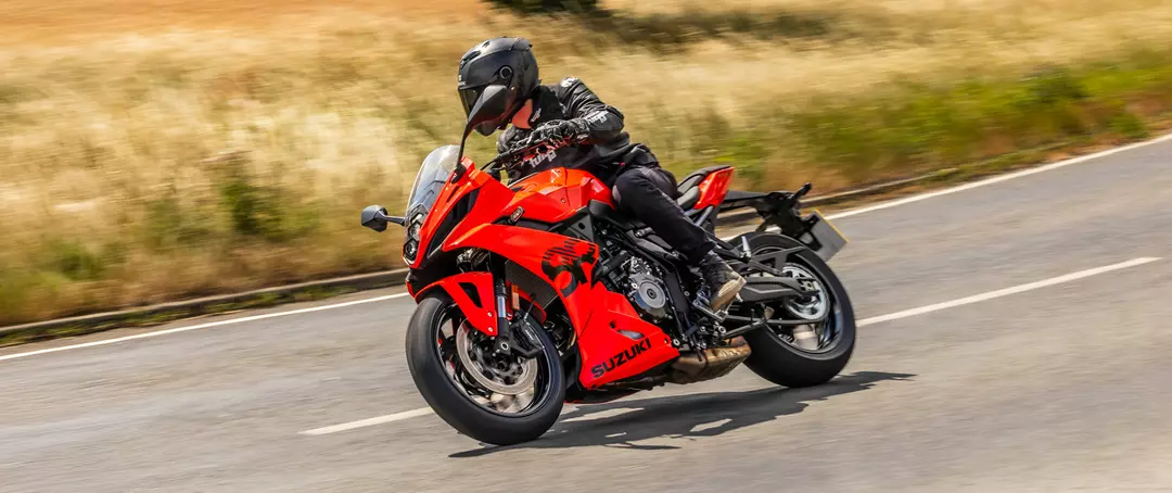 Suzuki GSX-8R leaning into a corner on the road with a grassy field behind