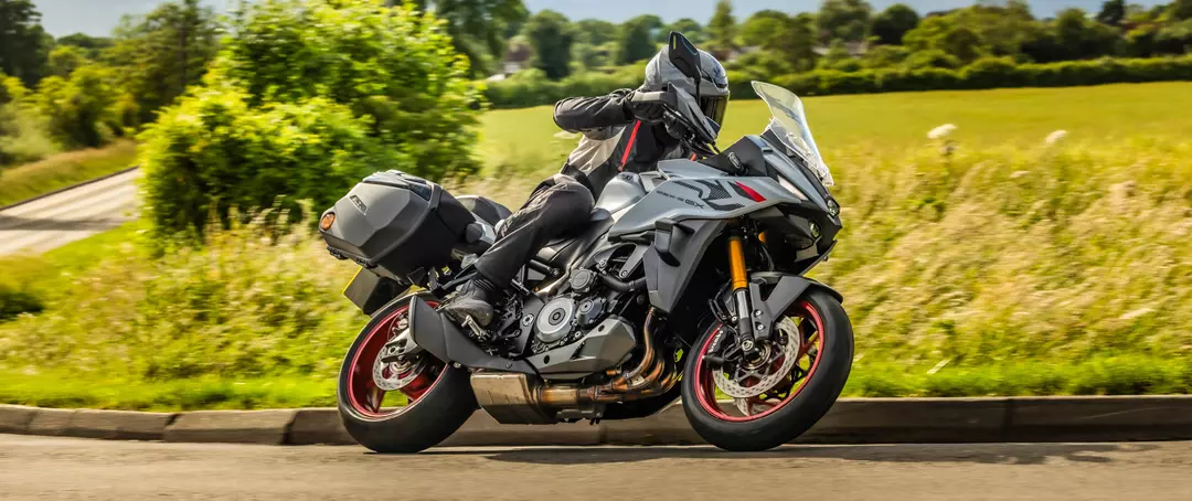 Suzuki GSX-S1000GX+ heading round a corner with country fields in the background.
