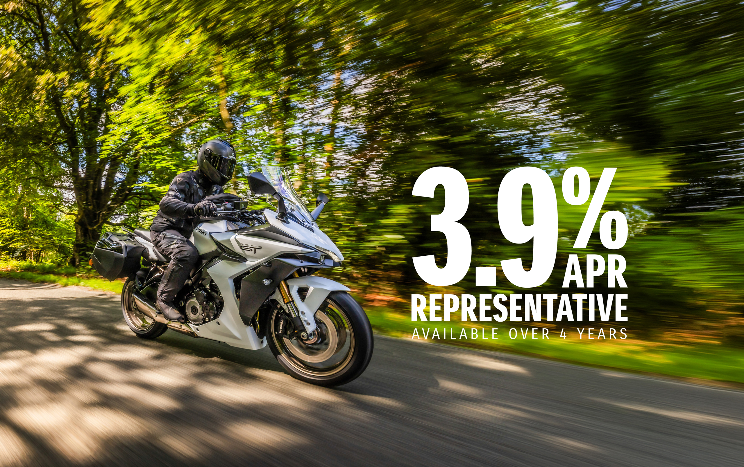 Suzuki GSX-S1000GT+ riding along a tree lined countryside road