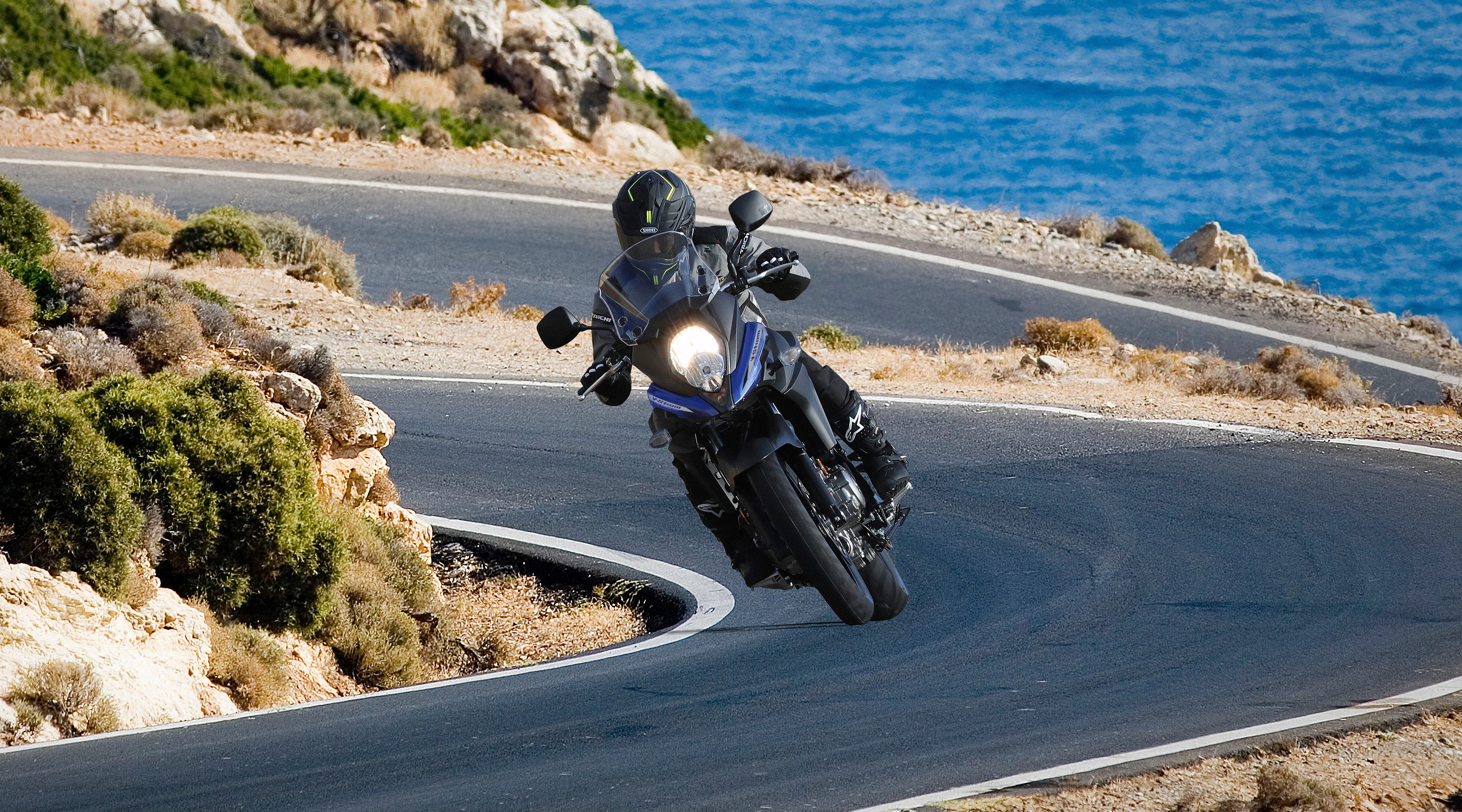 Suzuki V-Strom 650 on a twisty mountain road with the sea in the background