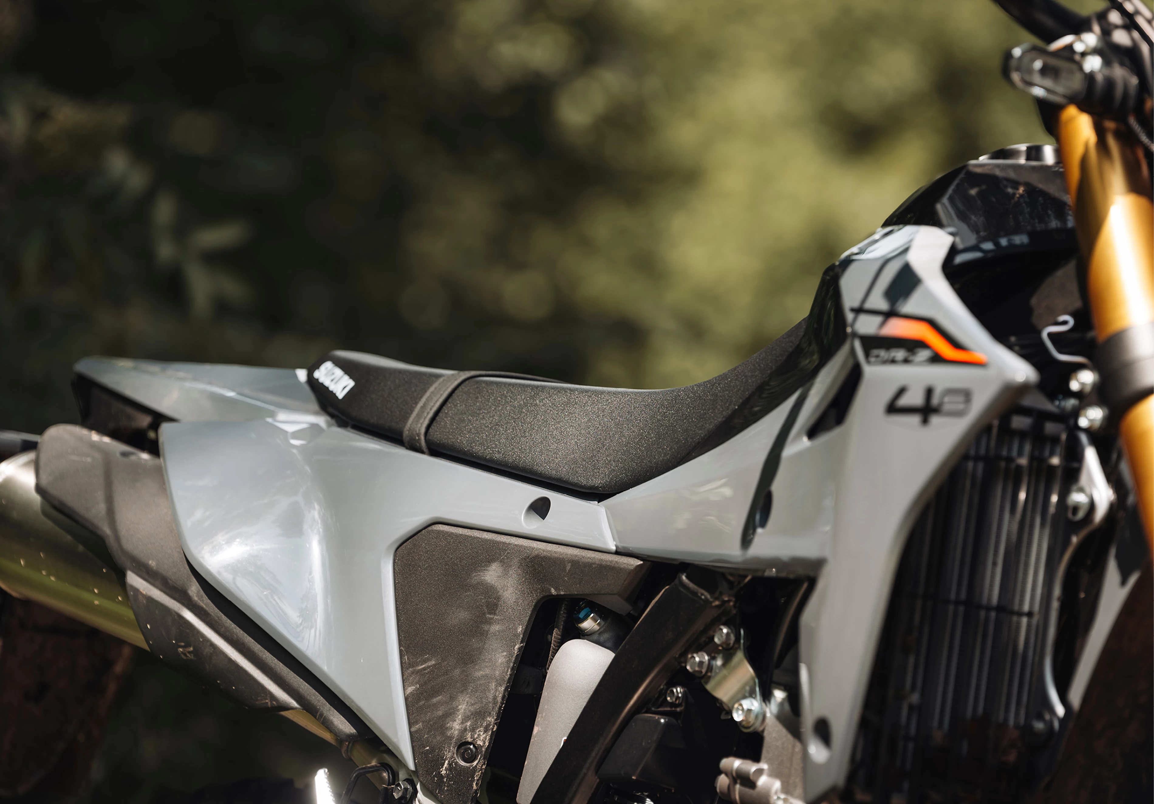 Suzuki DR-Z4S static in a forest focusing on the right hand side and the seat