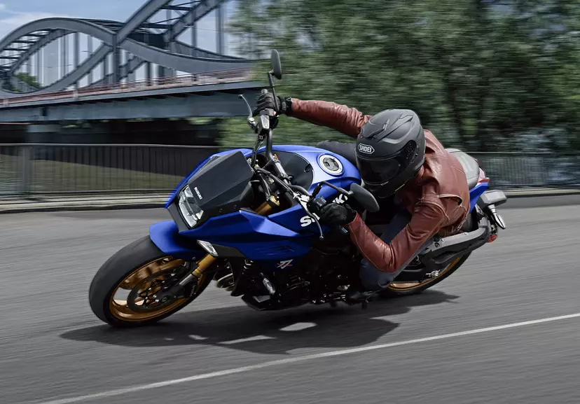 Suzuki Katana leaning over hard into a corner with bridge in the background.