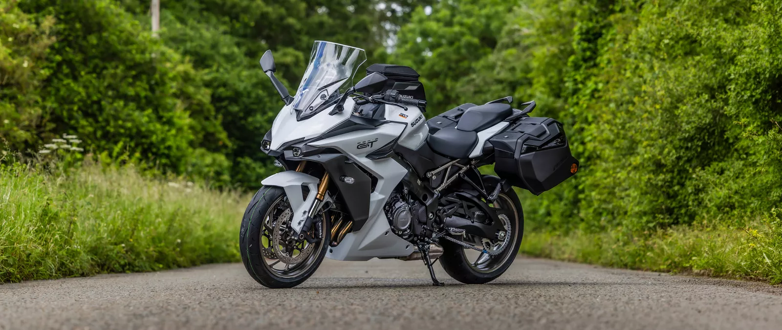 Suzuki GSX-S1000GT+ white static on location with trees behind, taken from the left hand front three quarters