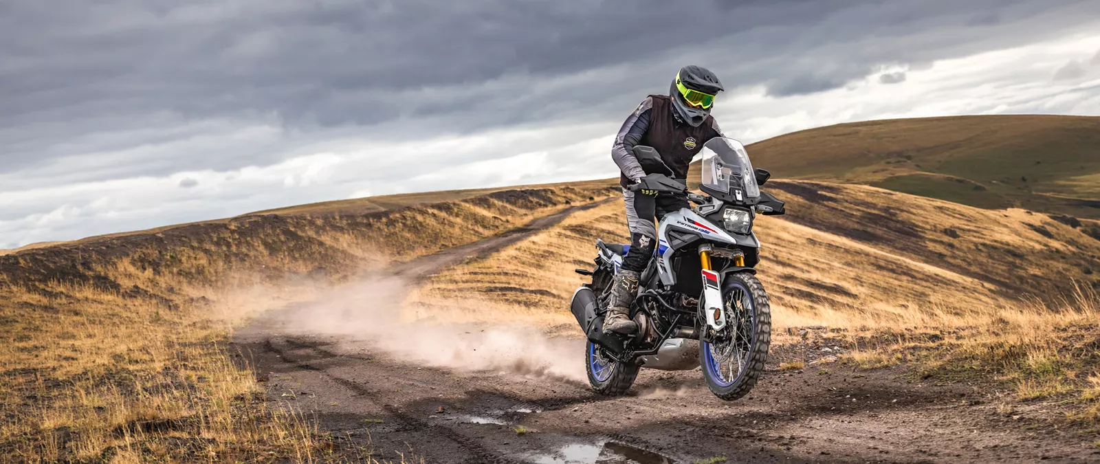 Suzuki V-Strom 1050DE white, pushing on along a mountain trail