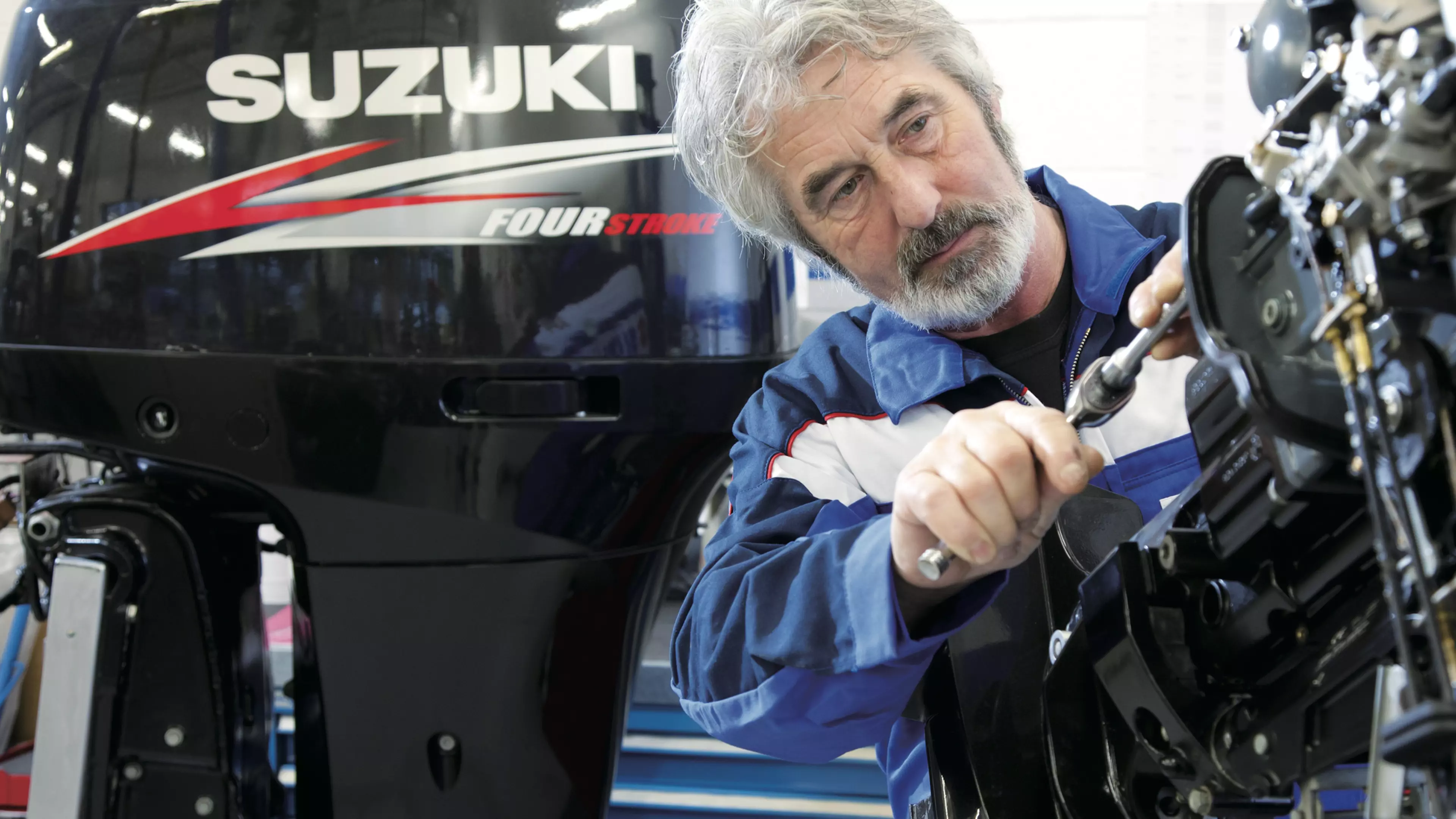 An engineering servicing a Suzuki outboard.