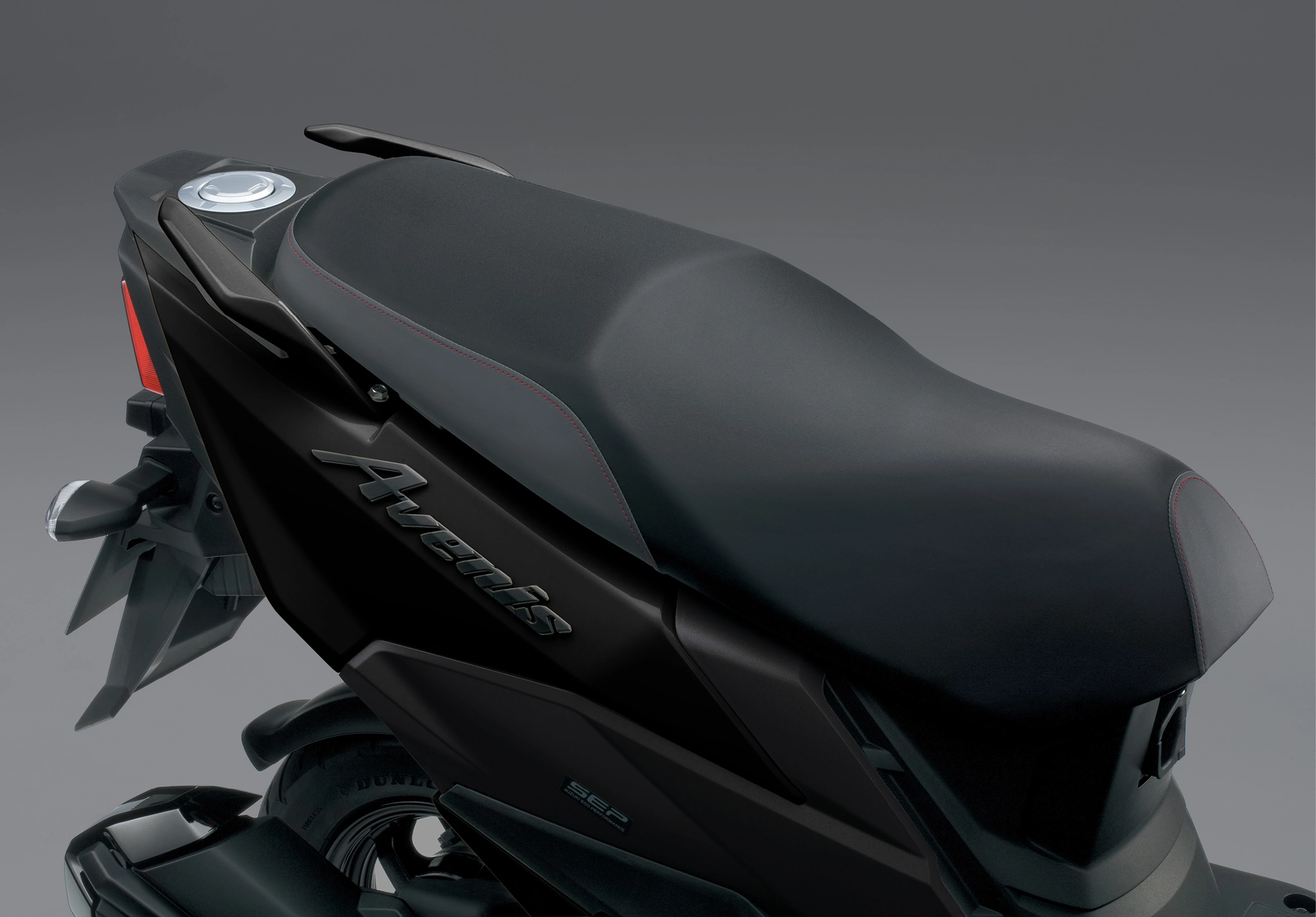 Suzuki Avenis 125 close-up of the seat design with a rider's hand resting on it, highlighting comfort and premium craftsmanship.