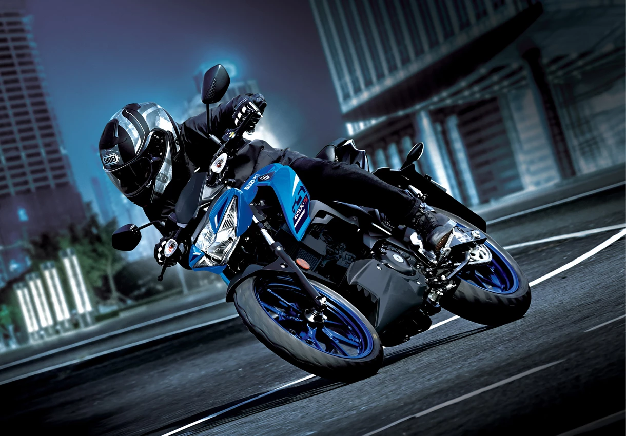 Suzuki GSX-S125 at night leaning into a corner with a city background.