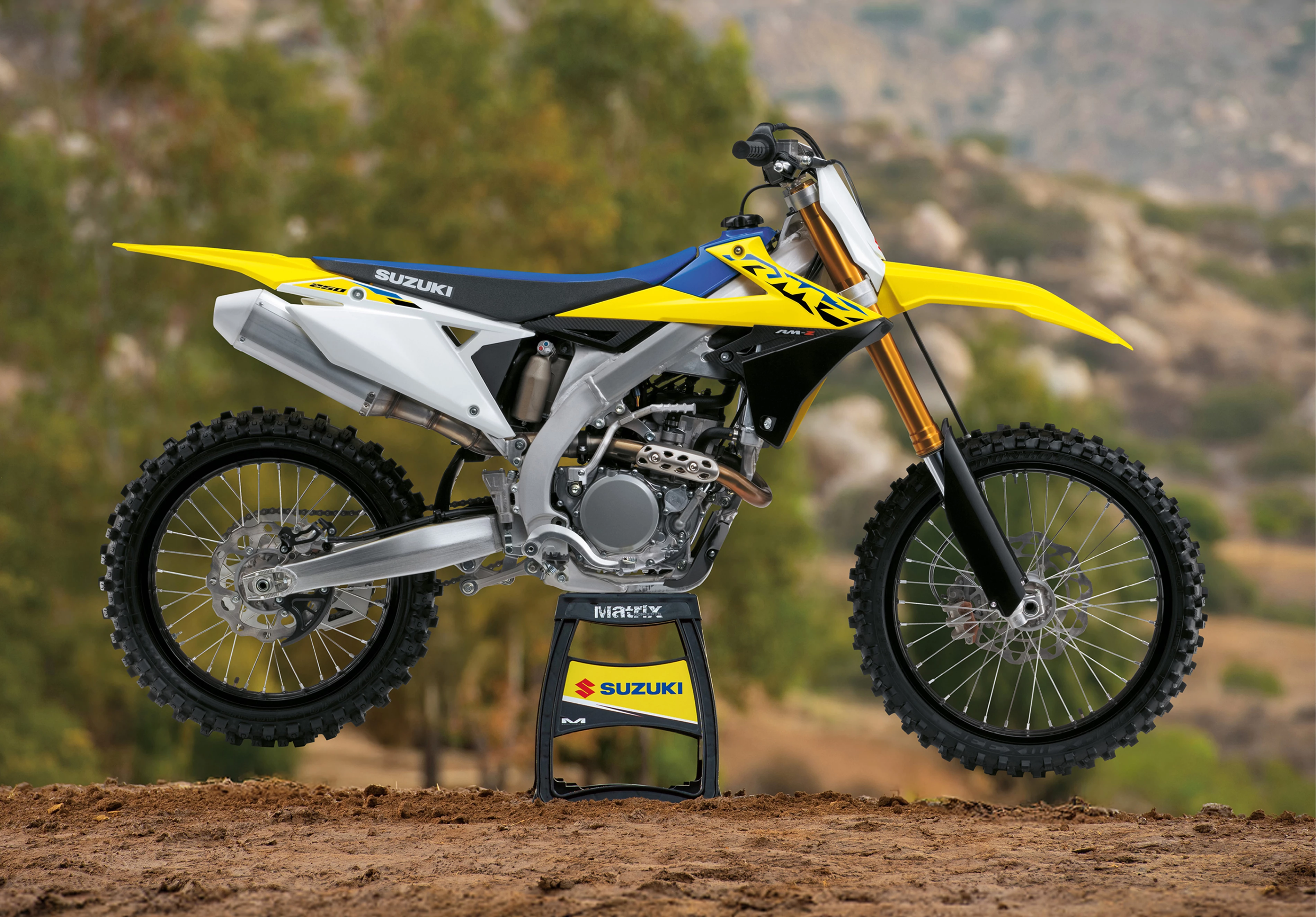 Suzuki RM-Z250 on a stand with mountains in the background