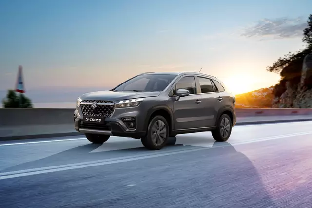 Side view of a grey Suzuki S-Cross on an scenic asphalt road at sunset.