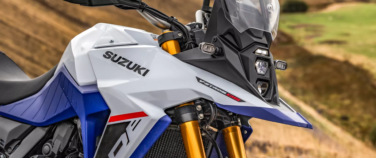 Suzuki V-Strom 800DE close up of Suzuki and 800DE logs with a hill behind