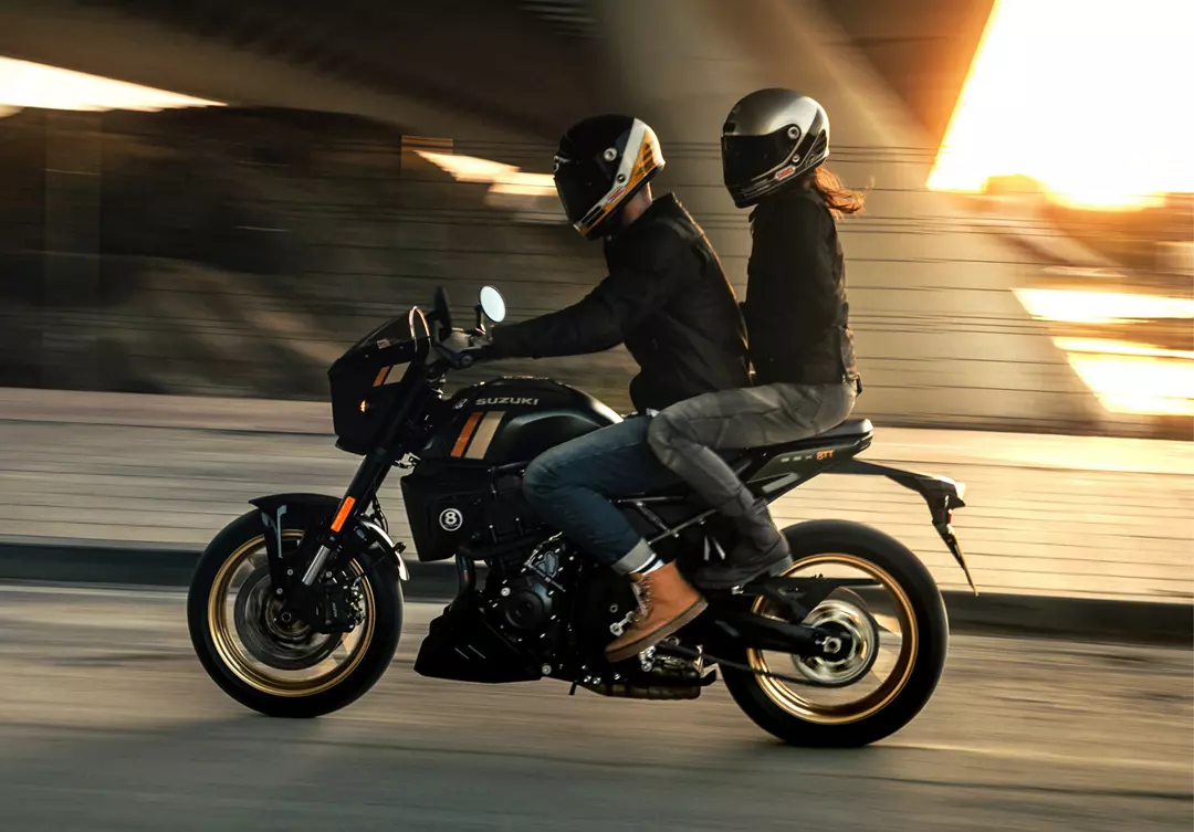 Suzuki GSX-8TT with pillion riding under a bridge at sunset
