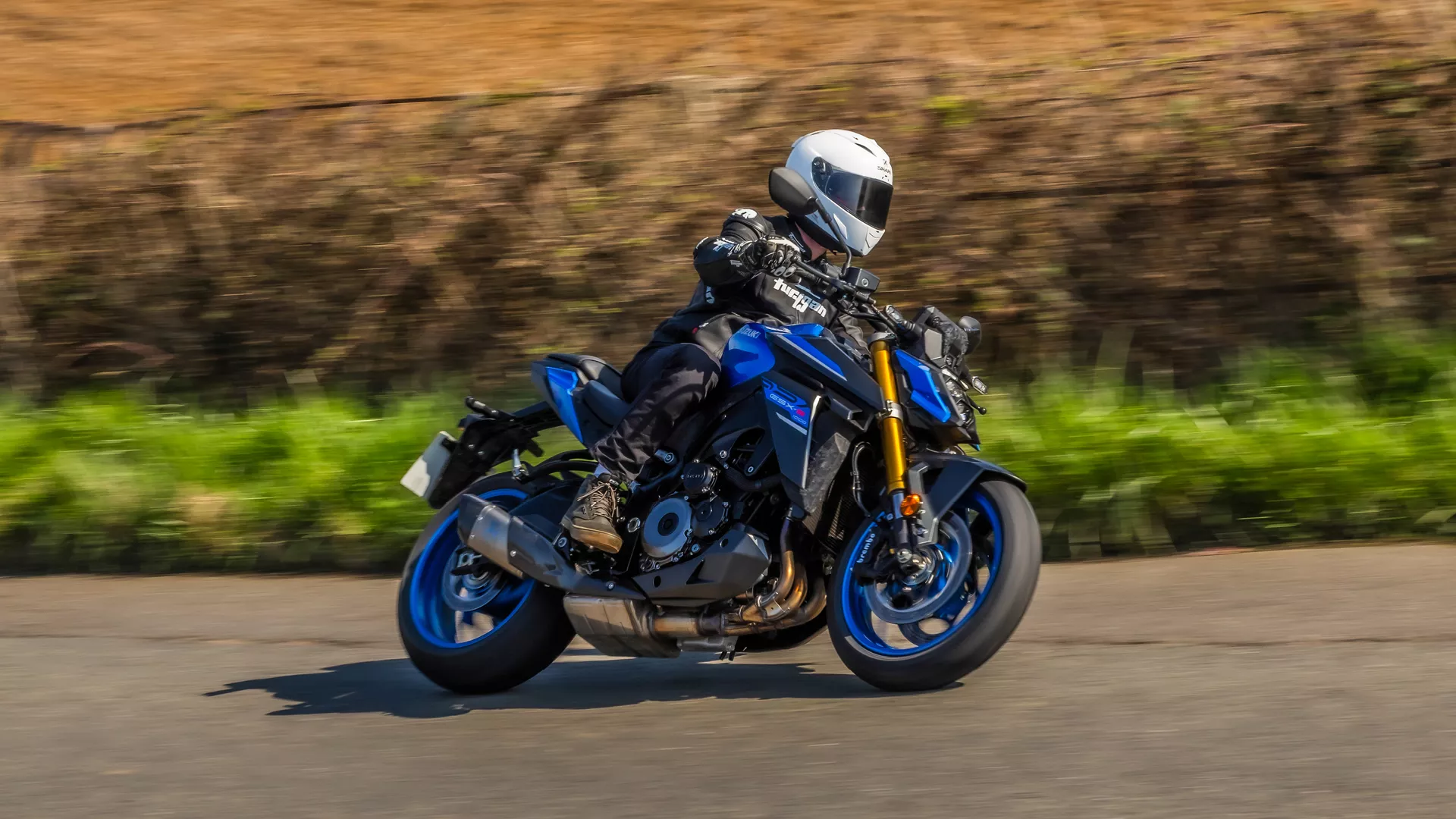 Suzuki GSX-S1000 blue leant over going around a corner on a country road