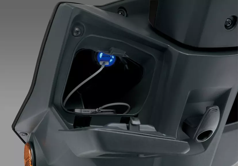 Suzuki Avenis 125 close-up of the left pocket storage area, featuring a USB charging port.