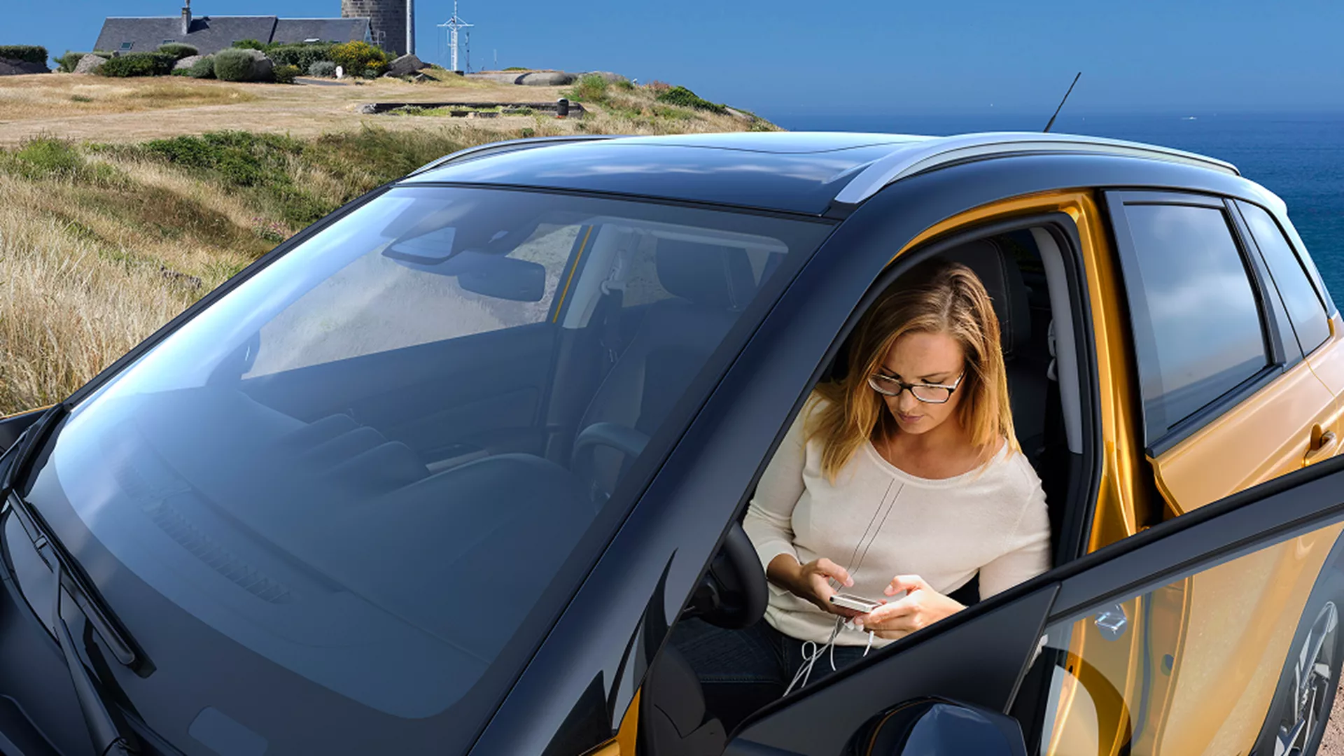Solar Yellow Vitara parked with women sitting texting in car with coastal view