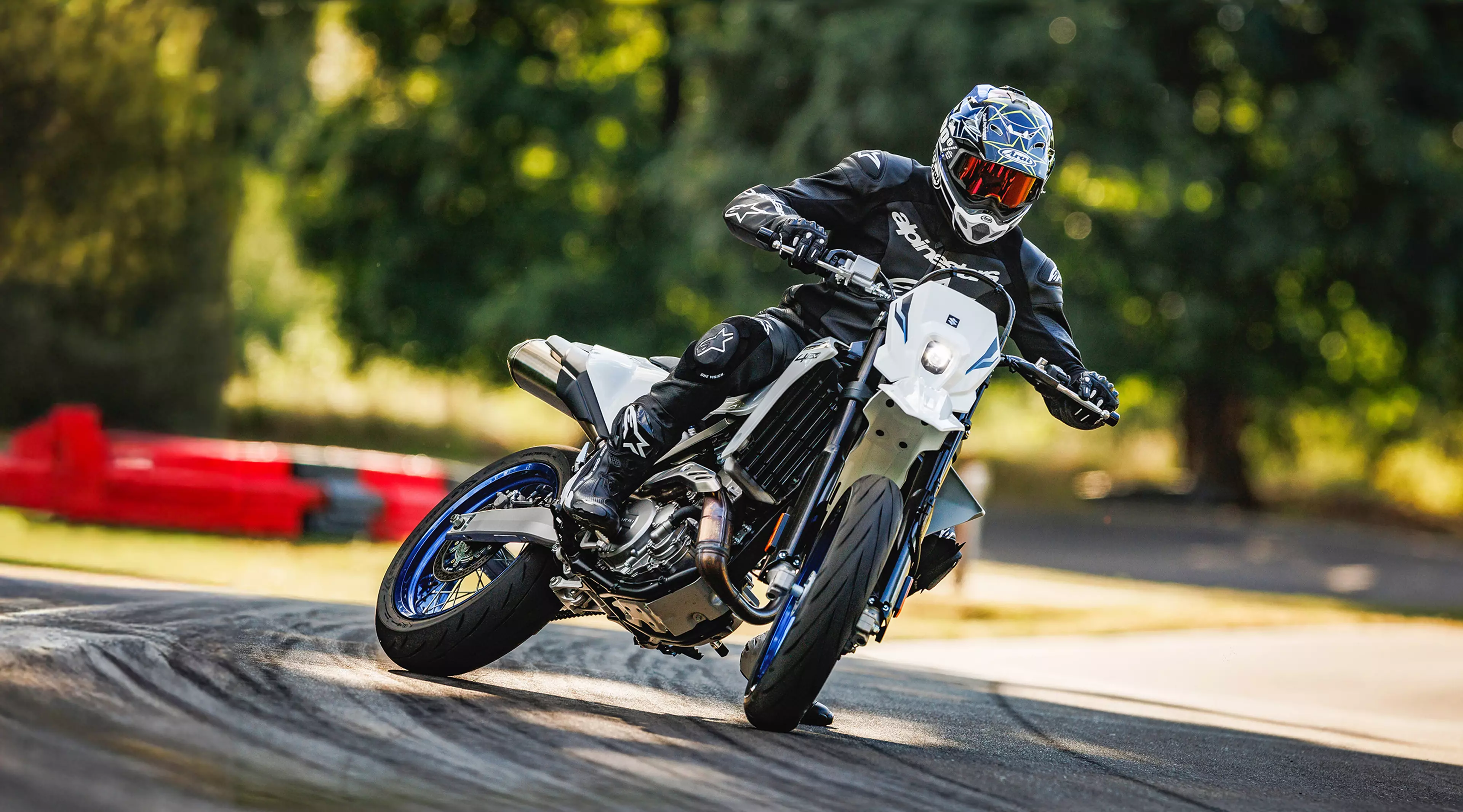 White Suzuki DR-Z4SM backing into a left hand corner on a sunny race track