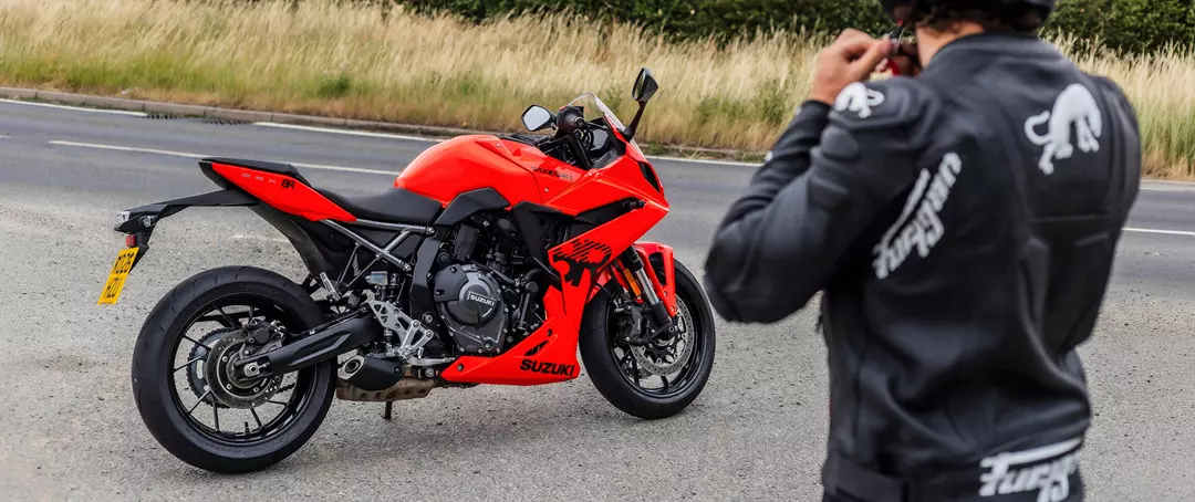Suzuki GSX-8R right hand side static with the ride to the right, tightening their helmet