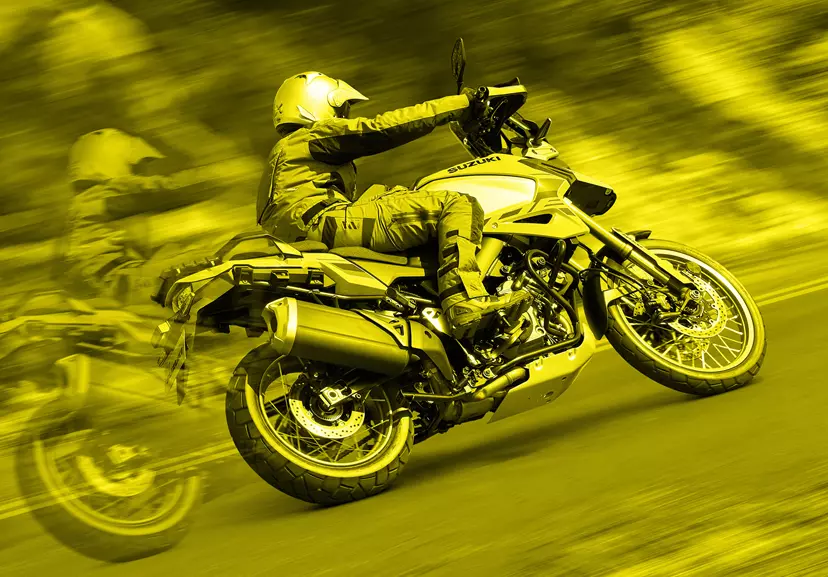 Suzuki V-Strom 1050DE motion blur, rider leaning gently into a corner