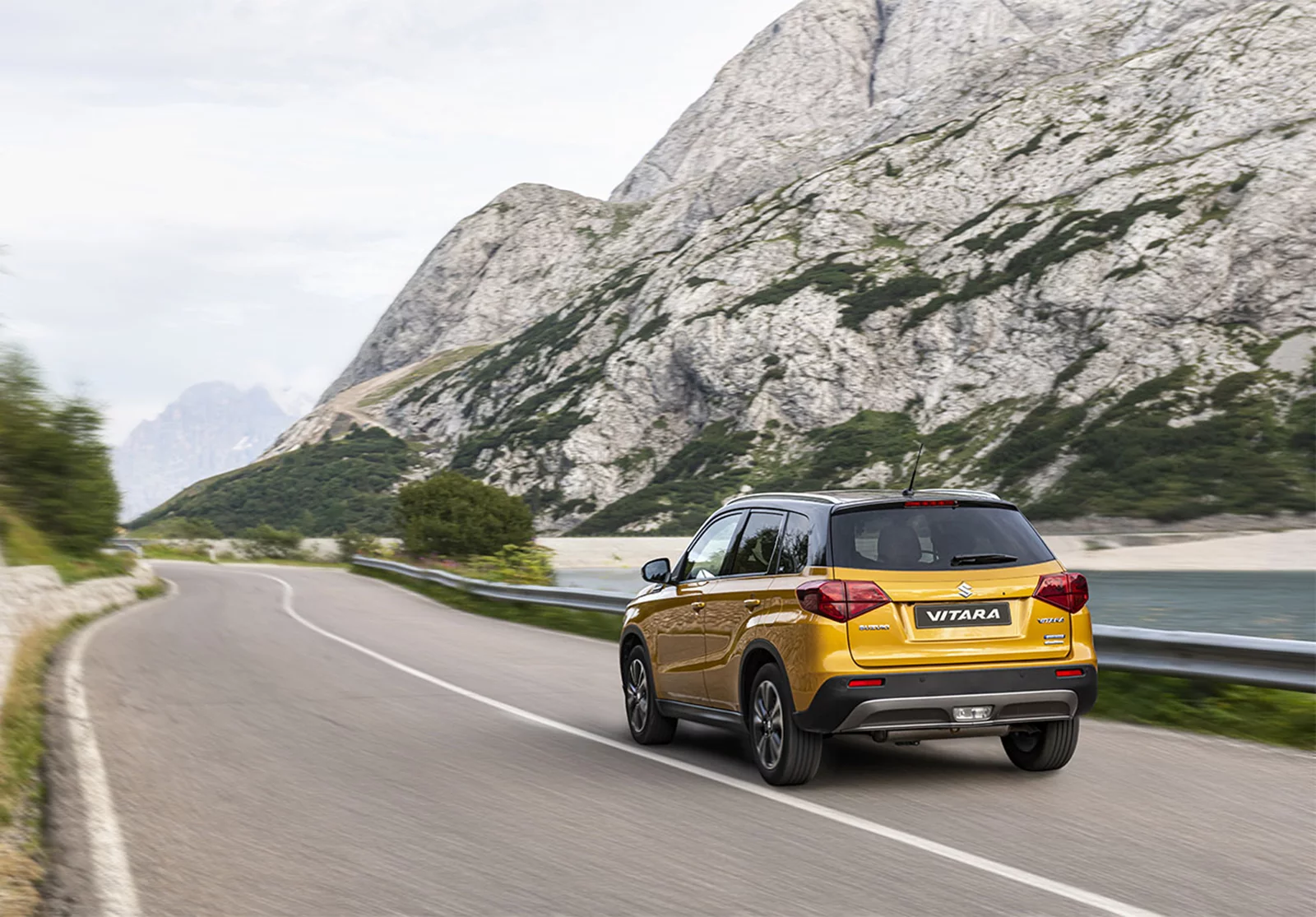 Solar yellow Suzuki Vitara driving on a mountainside