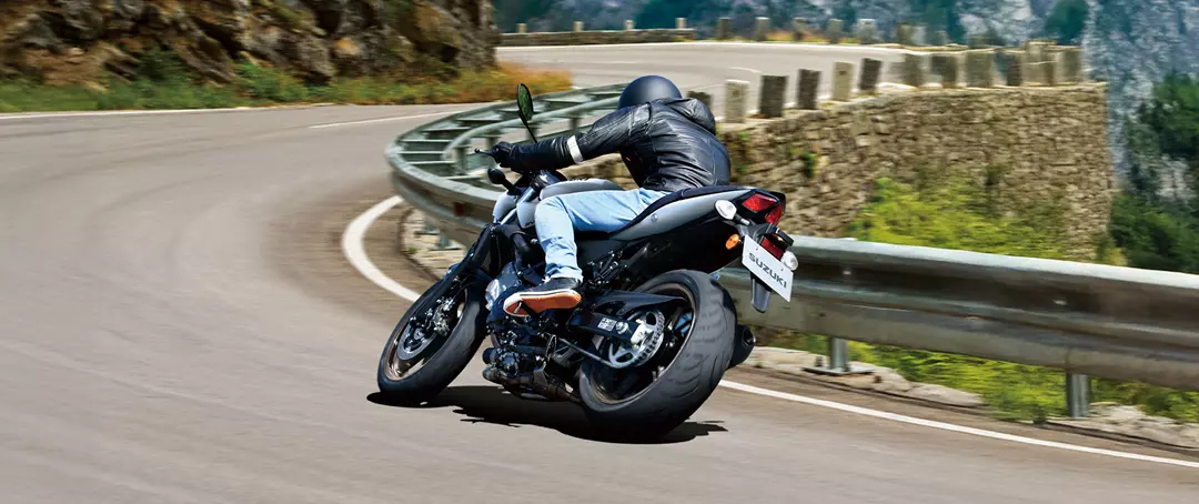 Suzuki SV650X leaning over and accelerating out a corner, rear shot