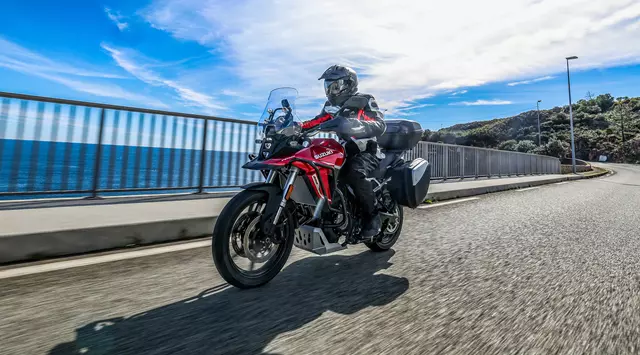 Suzuki V-Strom 800RE Tour riding across a bridge with the sea in the background