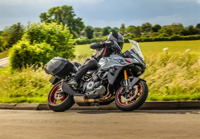 Suzuki GSX-S1000GX+ leaning into a corner with a field behind